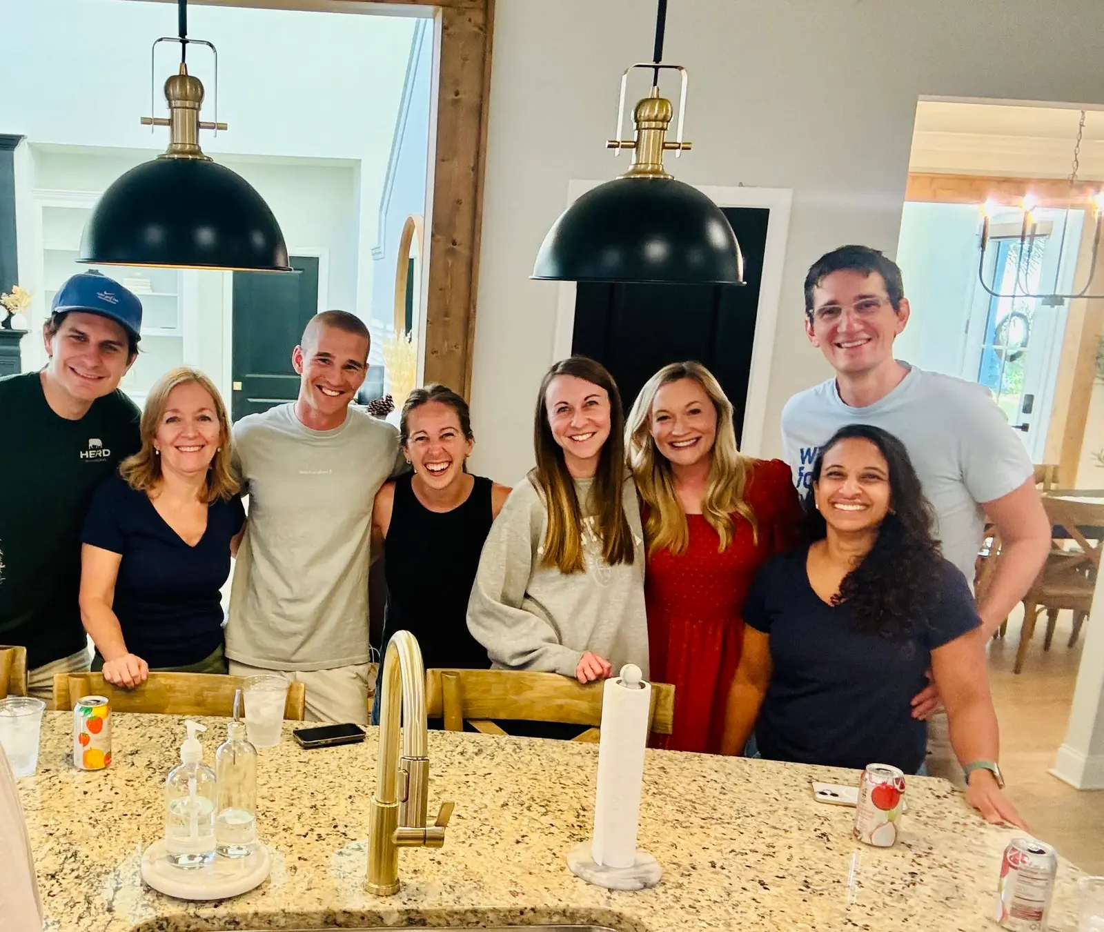 Friends smiling together around a kitchen island at a New City gathering