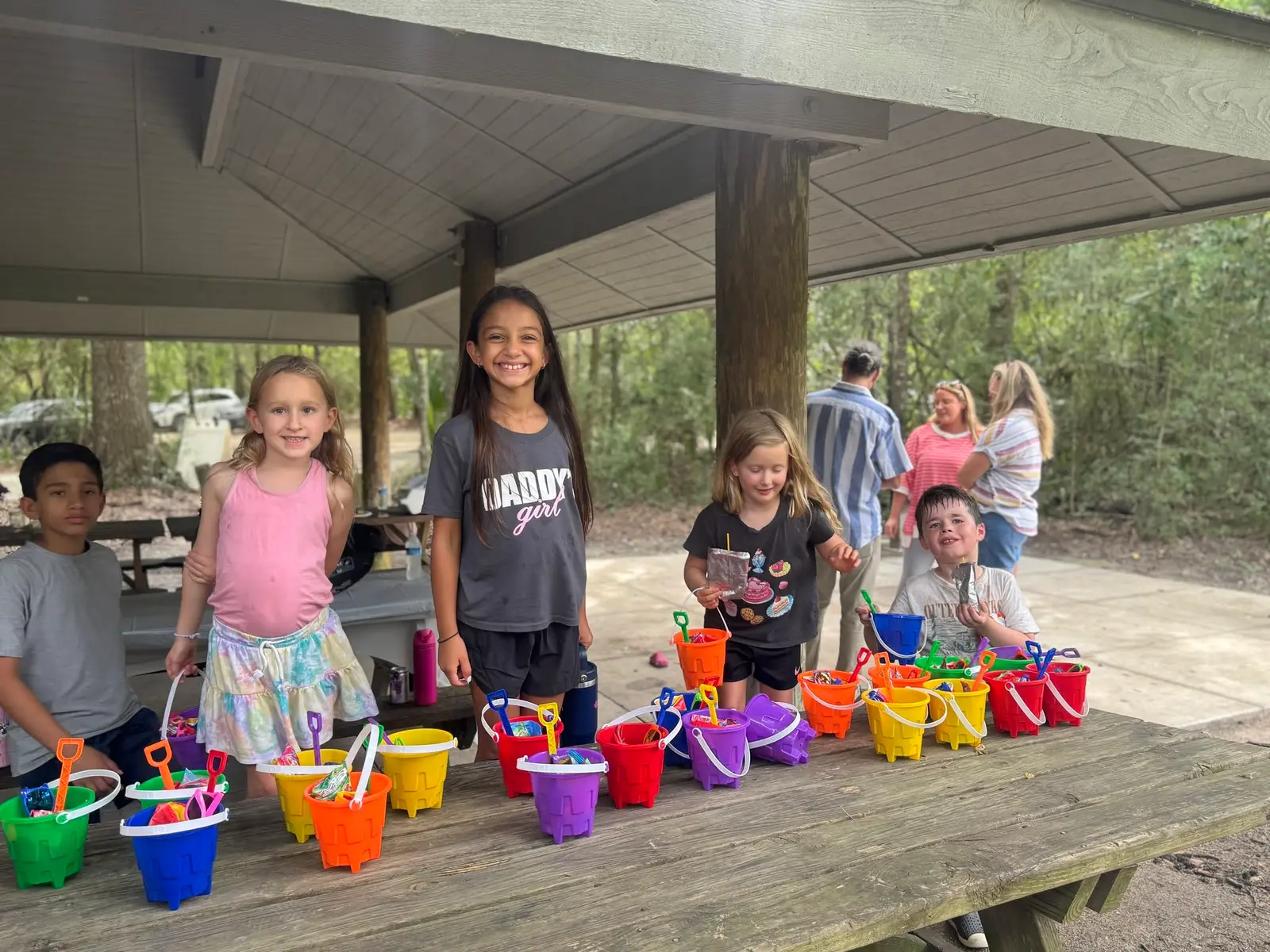Kids with colorful sand buckets at a New City picnic under a park pavilion