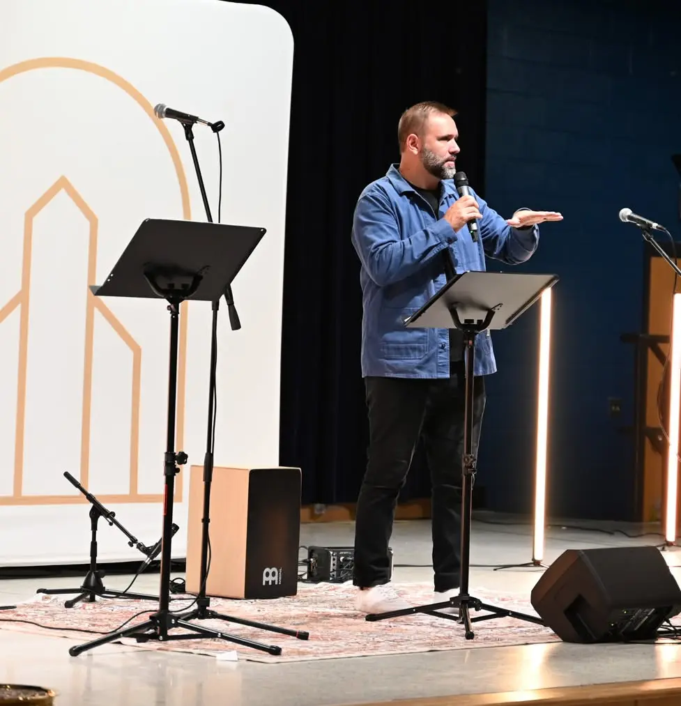 Pastor Drew Hensley preaching on stage at a New City Sunday service